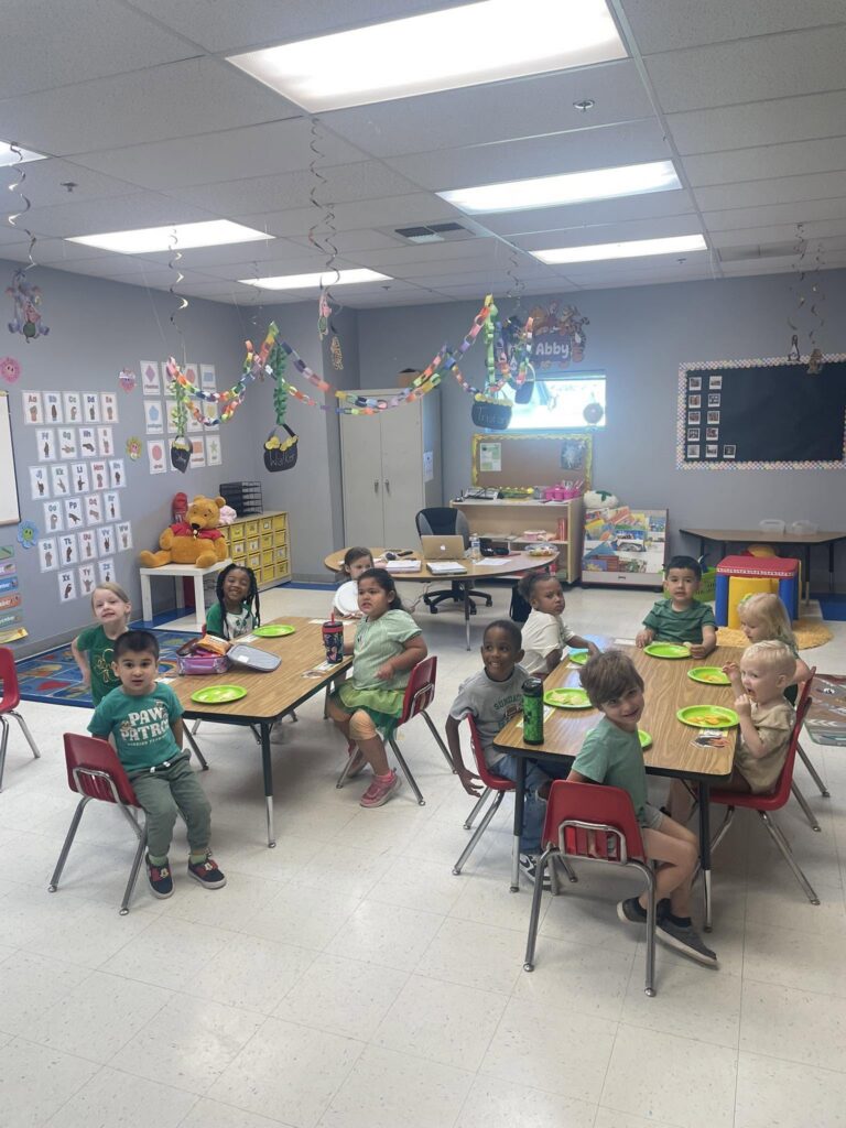 Children gathered around classroom tables for snack time