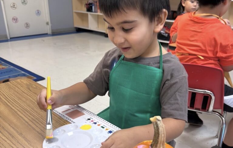 A child choosing paint colors for a pumpkin art project