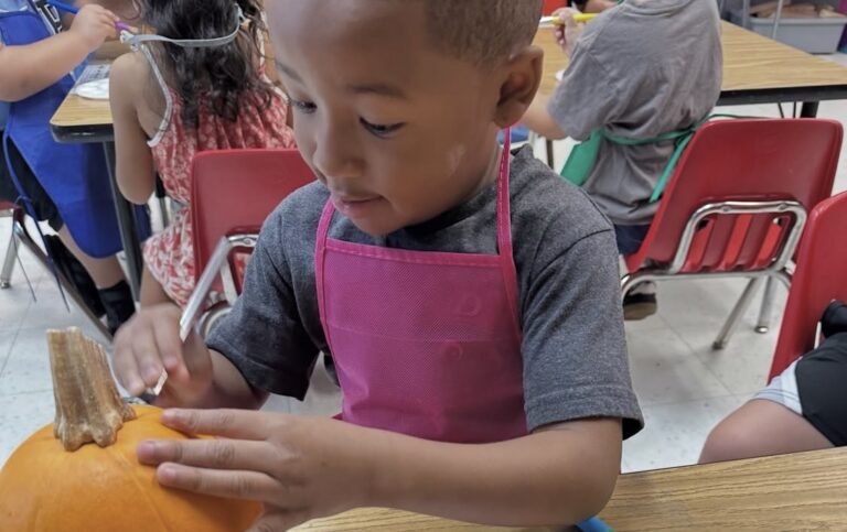 A child decorating a pumpkin during a classroom art activity